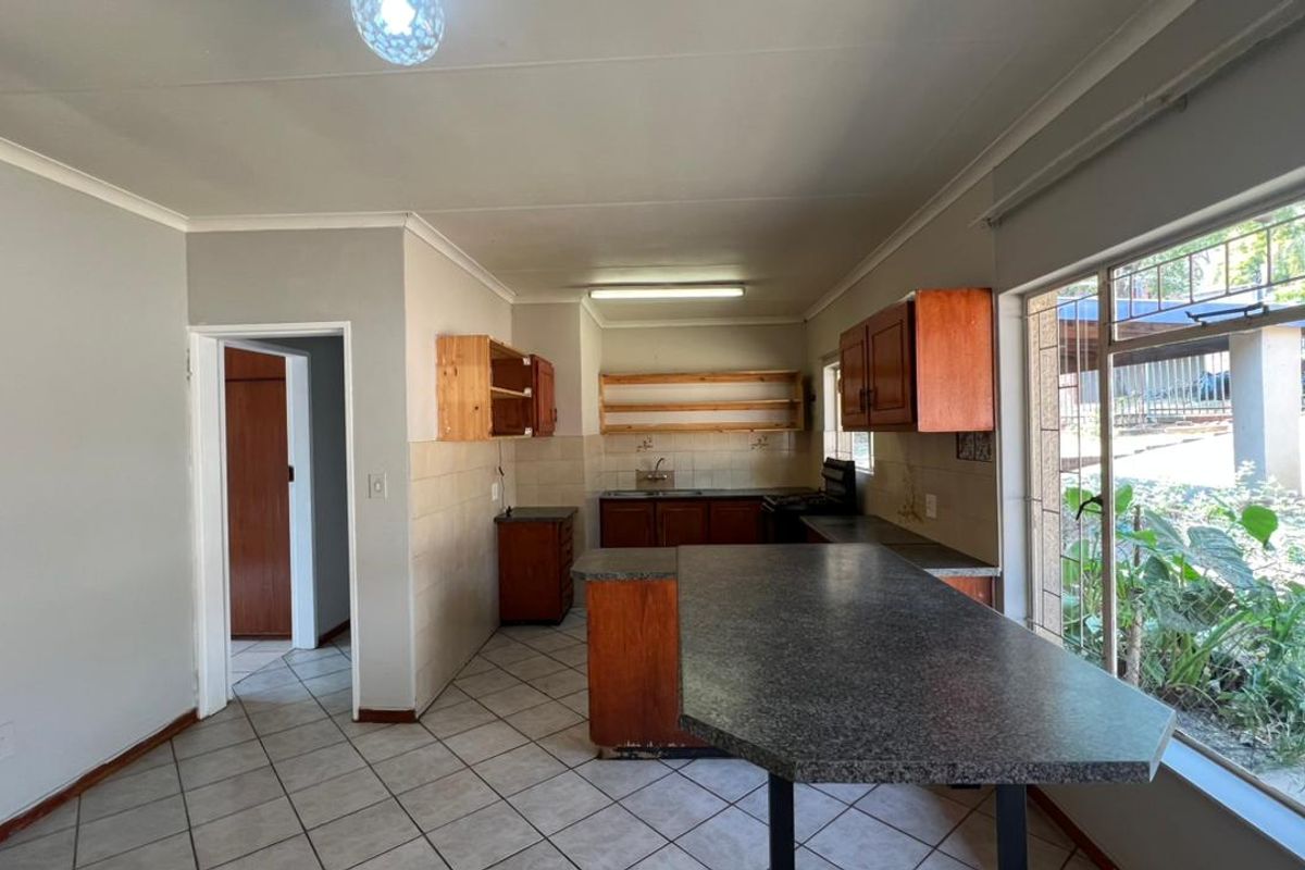 A functional kitchen space featuring tiled flooring, built-in cabinetry, a breakfast bar, and a tiled backsplash, offering potential for modern updates.