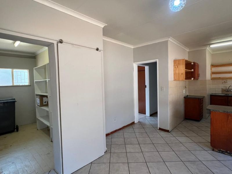 Open plan kitchen and utility area featuring tiled flooring, built-in cabinetry, and a separate pantry or scullery space.