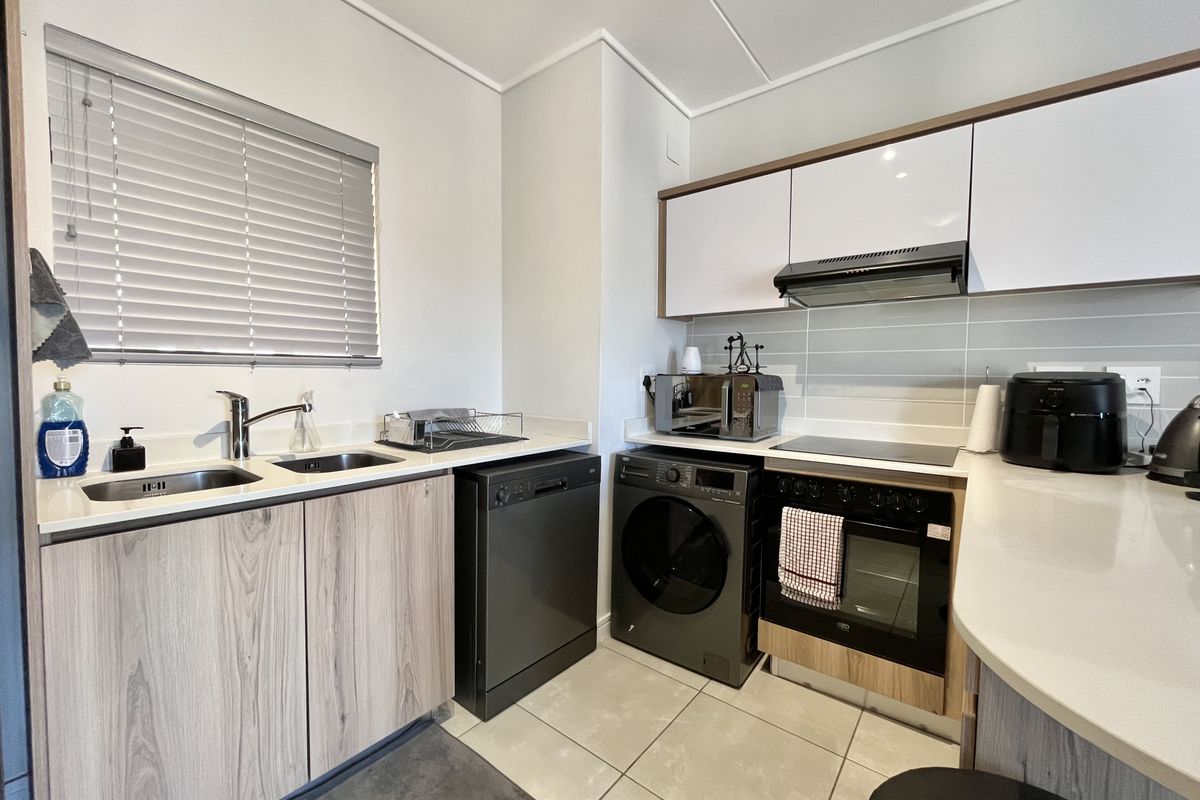 Modern kitchen featuring sleek cabinetry, stone countertops, integrated appliances, and a tiled backsplash, offering a functional and contemporary cooking space.