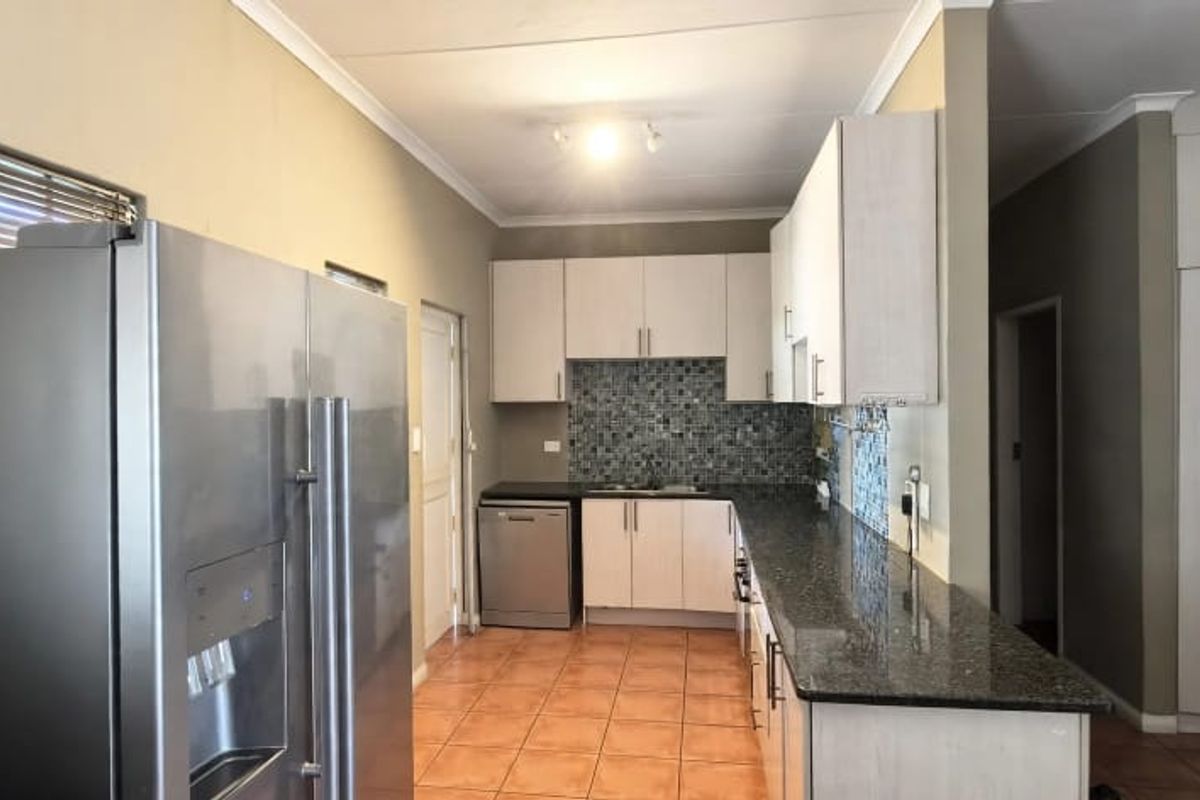 A functional kitchen featuring granite countertops, mosaic tile backsplash, ample built-in cabinetry, and ceramic floor tiles.