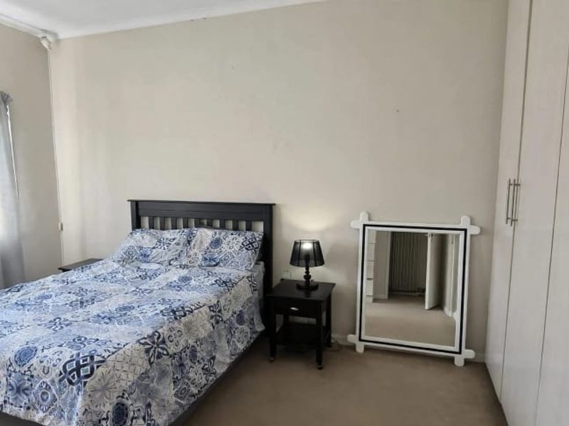 A bedroom featuring built-in cupboards, carpeted flooring, and an installed air conditioning unit.