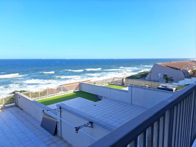 Spacious elevated balcony featuring tiled flooring, artificial grass sections, and a metal balustrade, offering expansive ocean views.