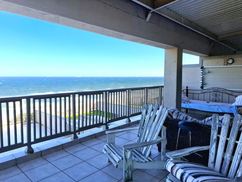 Spacious covered balcony featuring tiled flooring, a metal balustrade, and direct ocean views, offering a prime outdoor living space in need of minor maintenance.