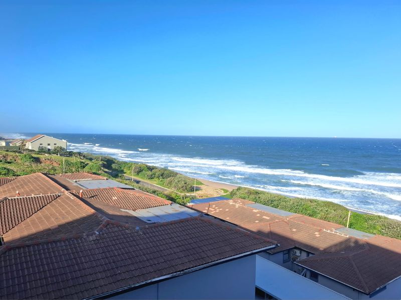 Elevated coastal view overlooking the ocean and surrounding residential rooftops.