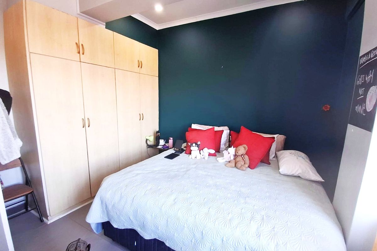 Bedroom featuring light wood built-in cupboards and a dark accent wall, providing functional storage and a modern aesthetic.