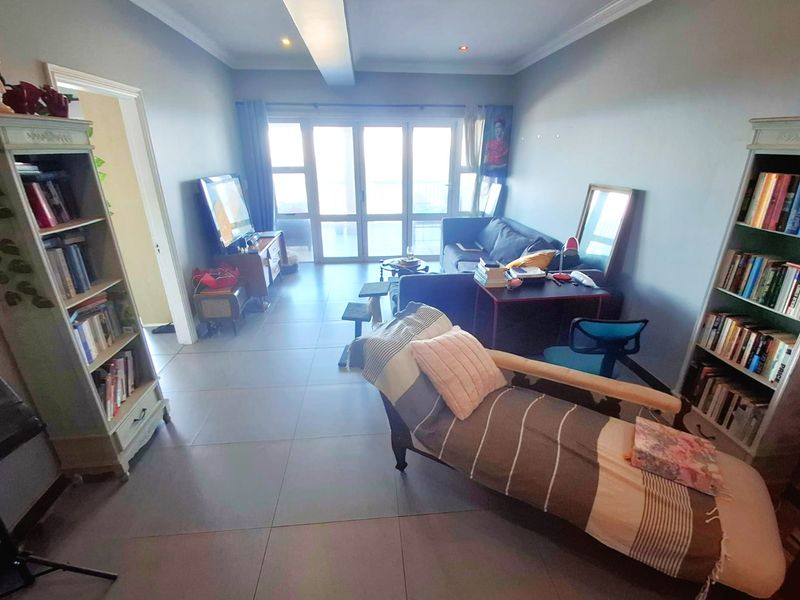 A spacious living room featuring large sliding glass doors that provide natural light and access to an outdoor area, complemented by neutral tiled flooring.