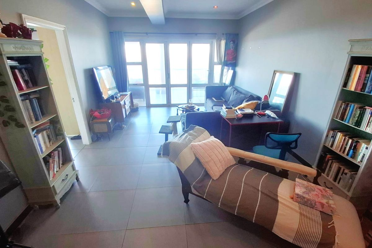 A spacious living room featuring large sliding glass doors that provide natural light and access to an outdoor area, complemented by neutral tiled flooring.