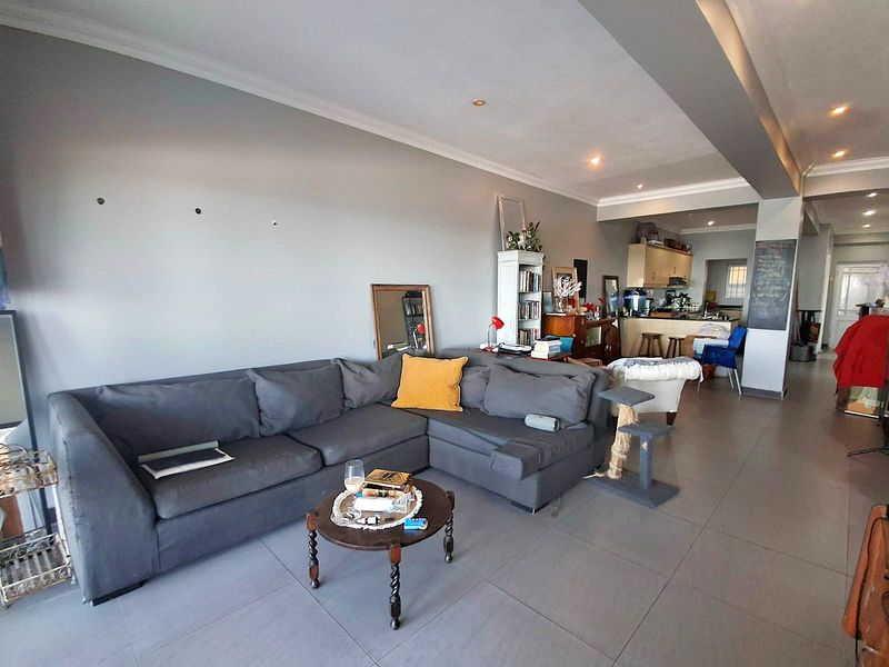 An open-plan living and kitchen area featuring tiled flooring, recessed lighting, and a functional kitchen layout with built-in cabinetry.