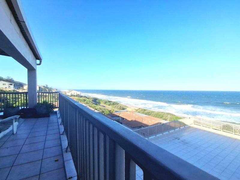 Spacious balcony featuring tiled flooring and a metal balustrade, offering expansive, unobstructed views of the coastline and ocean.