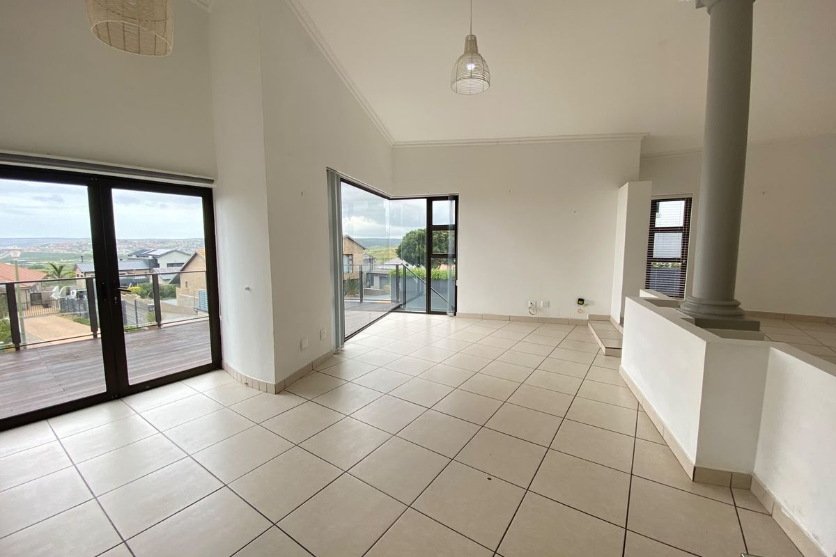 Spacious open-plan living area featuring neutral tiled flooring, a prominent structural column, and large glass sliding doors opening onto an outdoor deck.