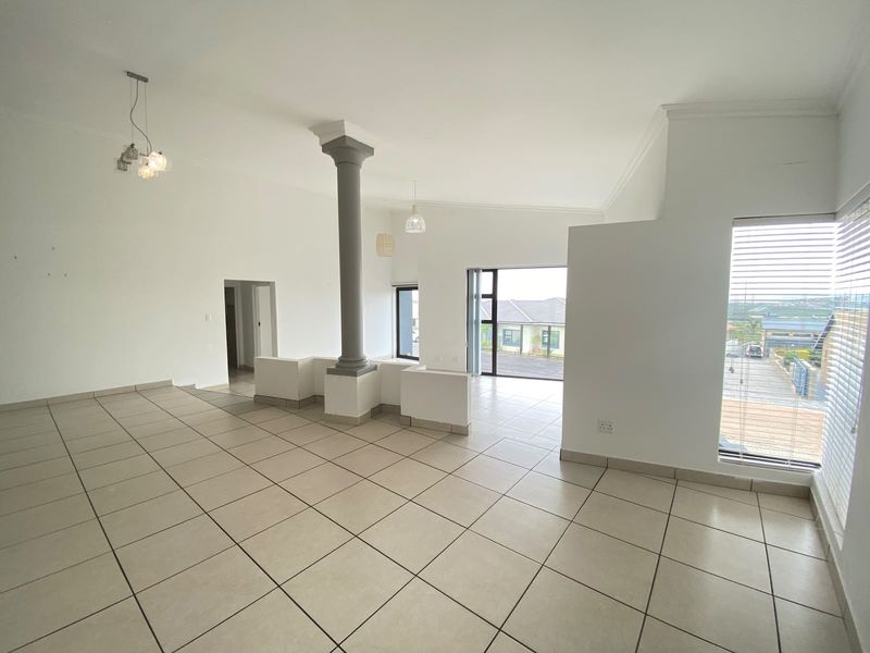 Spacious open-plan living area featuring neutral tiled flooring, a central structural column, and large sliding glass doors that provide ample natural light.
