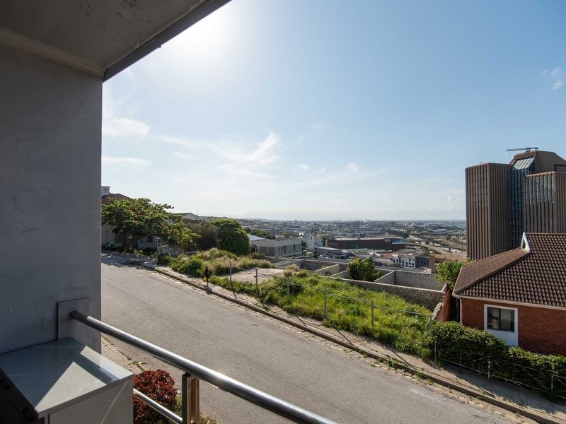 An elevated view overlooking the surrounding urban landscape and street from a balcony.