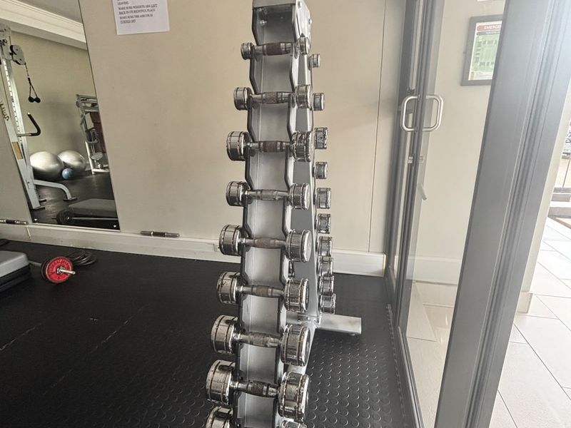 A functional gym space featuring rubber flooring, a wall-mounted pull-up bar, and a large mirror, providing a dedicated area for fitness activities.