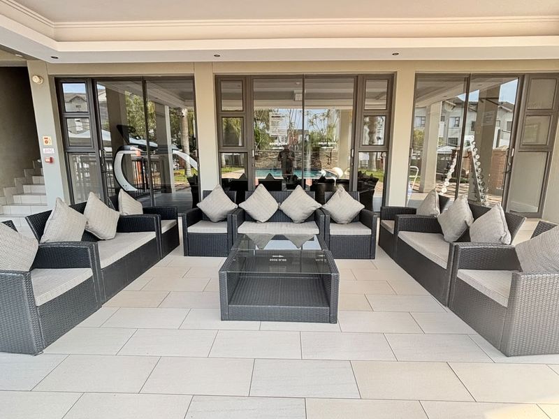 A spacious, well-maintained covered patio featuring large sliding glass doors and modern tiled flooring, ideal for outdoor relaxation and entertaining.