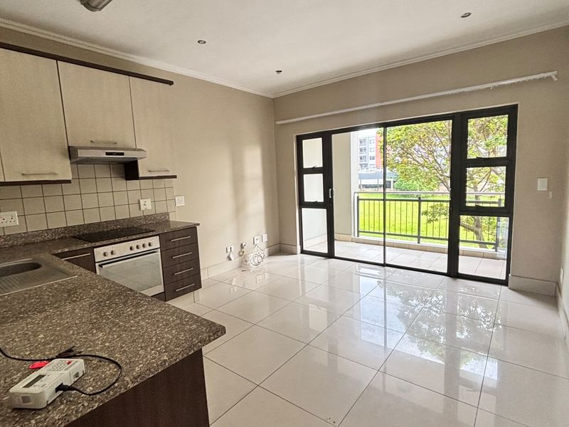 Spacious open-plan kitchen and living area featuring modern tiled floors, built-in cabinetry, and large sliding doors leading to a private balcony.