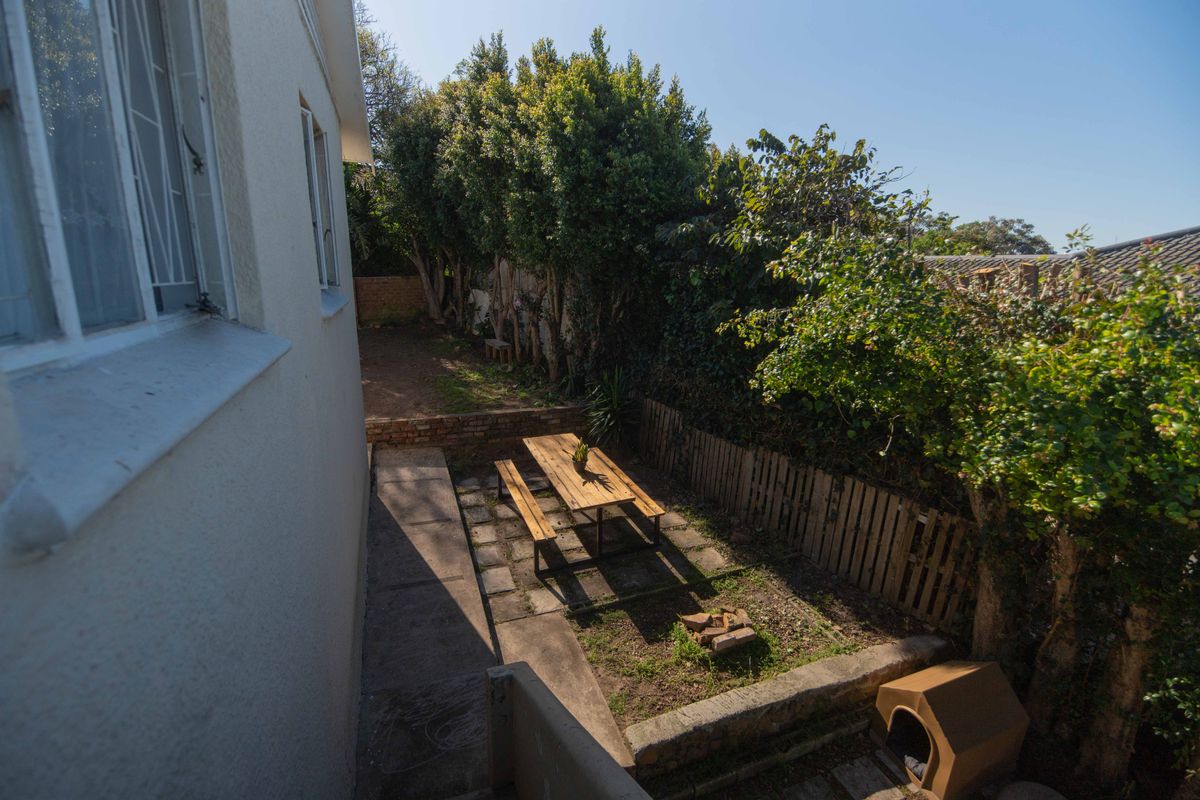 A rear garden area featuring paved sections, a retaining wall, and perimeter timber fencing, offering a private outdoor space.