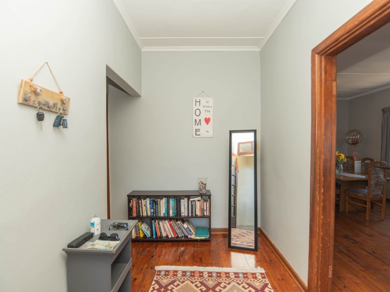 A functional hallway featuring polished timber flooring and a classic timber door frame leading into the adjacent living area.