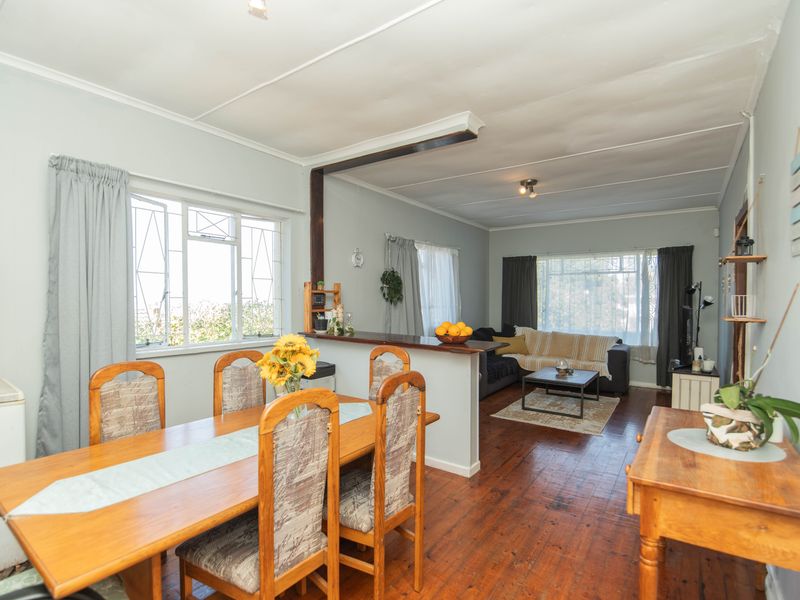 Open-plan living and dining area featuring original timber flooring, a central breakfast bar, and large windows providing ample natural light.