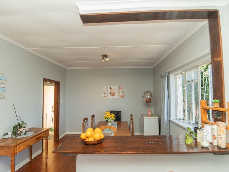 Open plan living and dining area featuring timber flooring, a breakfast bar, and large windows allowing for natural light.