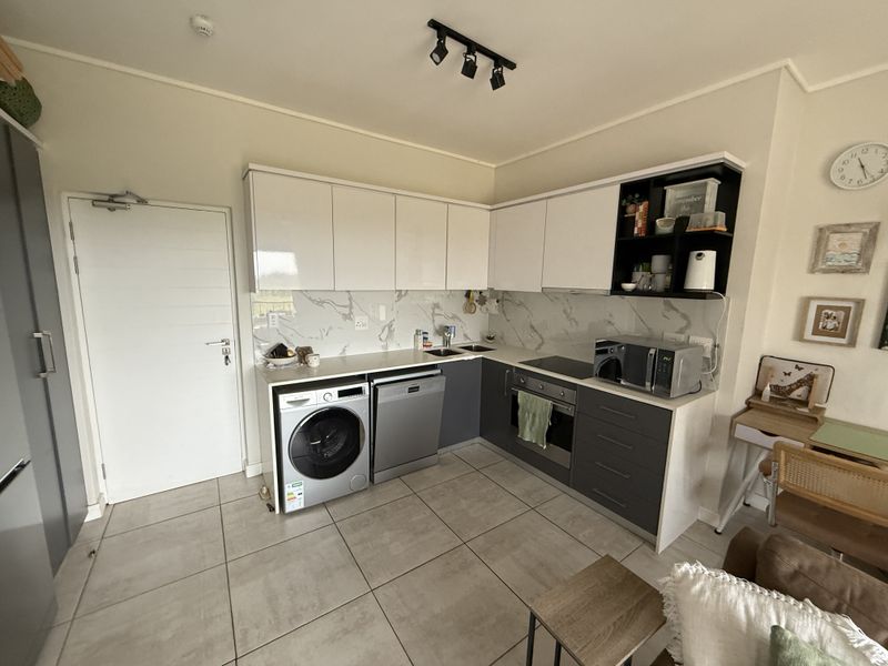 Modern kitchen featuring sleek white and grey cabinetry, marble-look splashback, integrated appliances, and tiled flooring in an open-plan layout.
