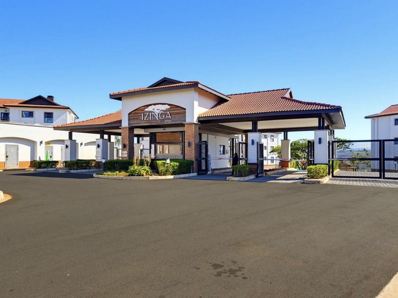 The main entrance and security gatehouse of the Izinga apartment complex, featuring a well-maintained brick and tile facade with paved driveway access.