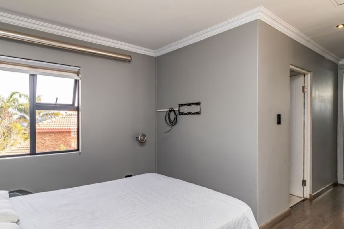 A well-maintained bedroom featuring laminate flooring, crown molding, recessed lighting, and a built-in wardrobe with a mirrored door.