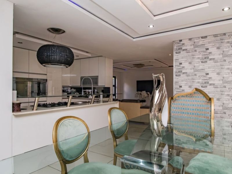 Modern open-plan kitchen and dining area featuring sleek cabinetry, a gas hob, recessed lighting, and a decorative stone feature wall.