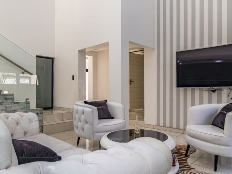 Modern living room featuring a striking stone-clad staircase with a glass balustrade, high ceilings, and a contemporary striped feature wall.