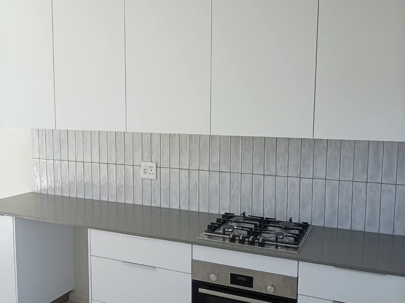 Modern kitchen featuring sleek white cabinetry, stone countertops, a tiled backsplash, and integrated Bosch oven and gas hob.