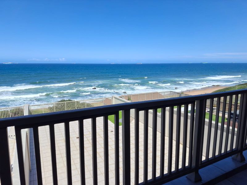 Spacious balcony featuring tiled flooring and a secure railing, offering expansive, unobstructed views of the ocean and coastline.