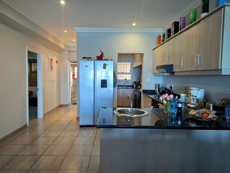 Open-plan kitchen featuring granite countertops, ample built-in cabinetry, and a functional layout with a secondary scullery area visible in the background.