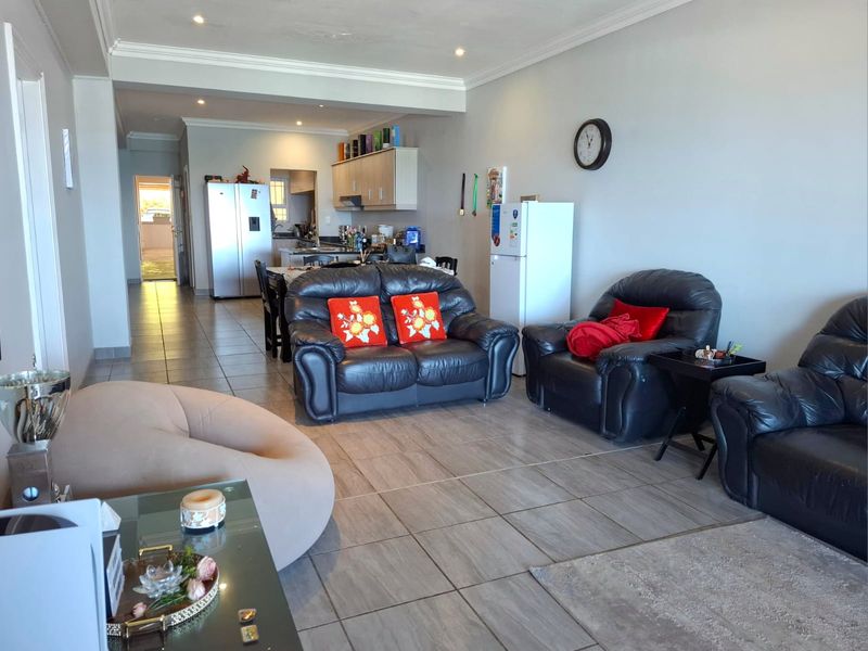 Spacious open-plan living and kitchen area featuring tiled flooring, recessed lighting, and functional cabinetry, offering a versatile layout for modern apartment living.