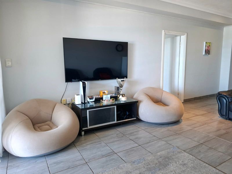 A living room area featuring neutral tiled flooring and decorative ceiling molding, providing a clean and functional space.