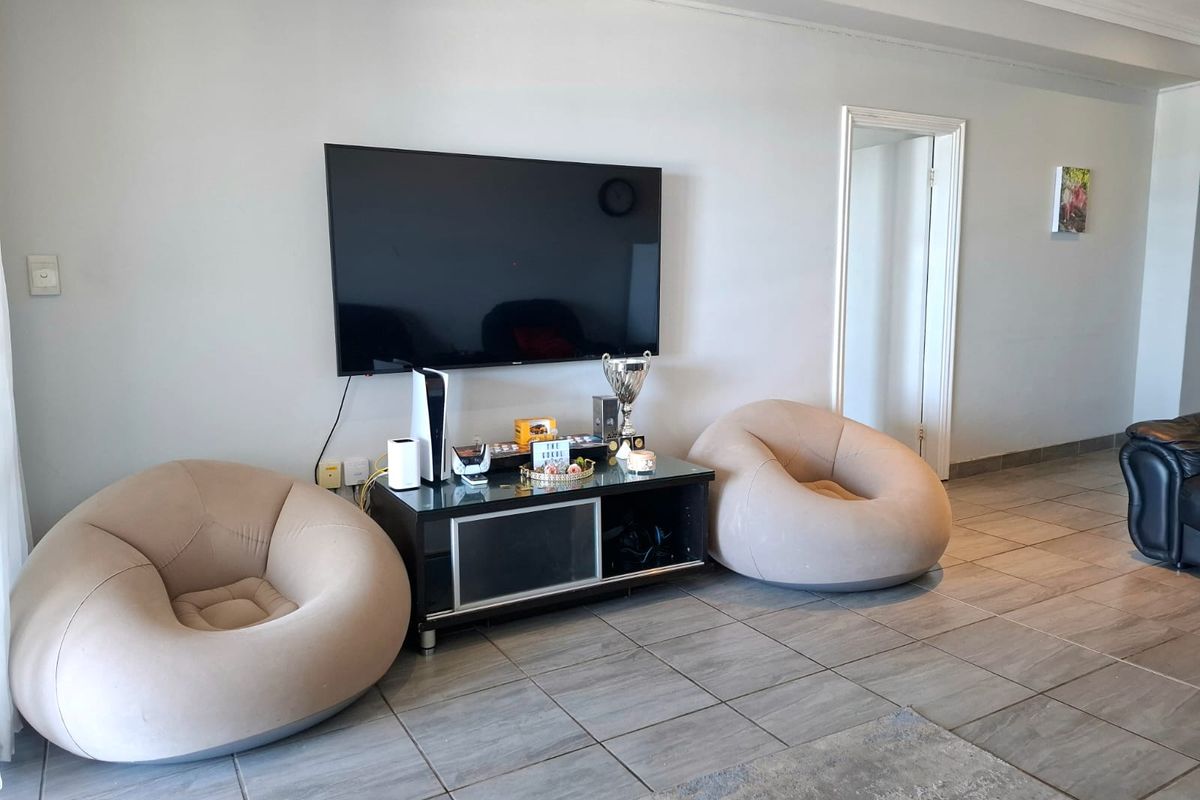 A living room area featuring neutral tiled flooring and decorative ceiling molding, providing a clean and functional space.