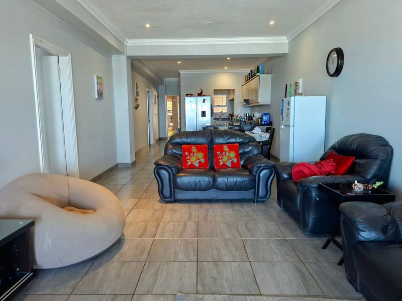Open plan living and kitchen area featuring tiled flooring, recessed lighting, and neutral wall finishes, providing a functional and connected living space.