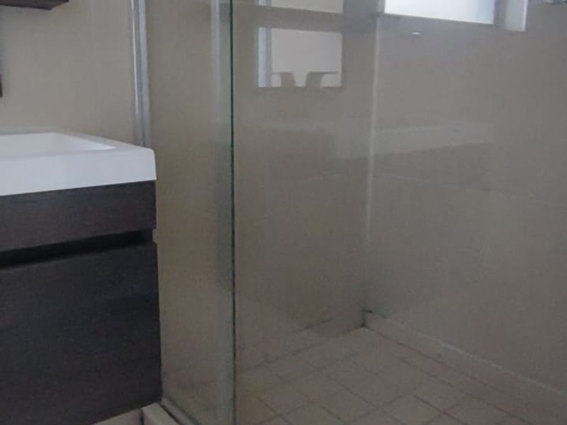 A compact bathroom featuring a glass-enclosed shower with tiled flooring and a modern wall-mounted vanity unit.