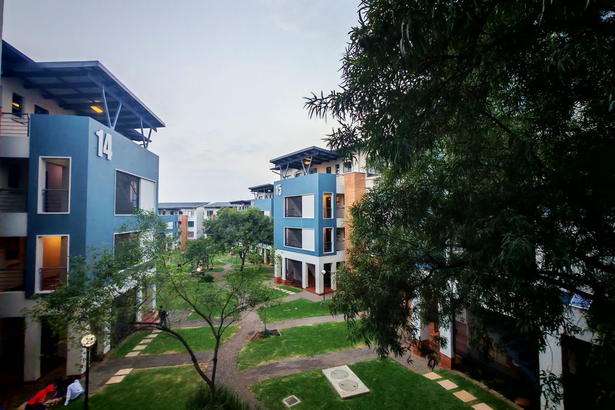 A view of the landscaped communal garden area situated between multi-story apartment blocks, featuring paved pathways and well-maintained green spaces.