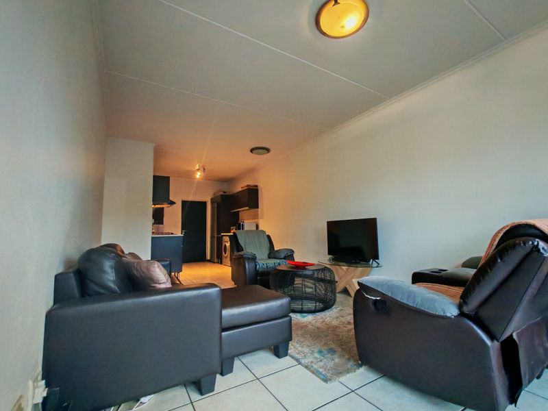 Open-plan living area featuring tiled flooring and a compact kitchen space with built-in cabinetry, offering a functional layout for modern apartment living.