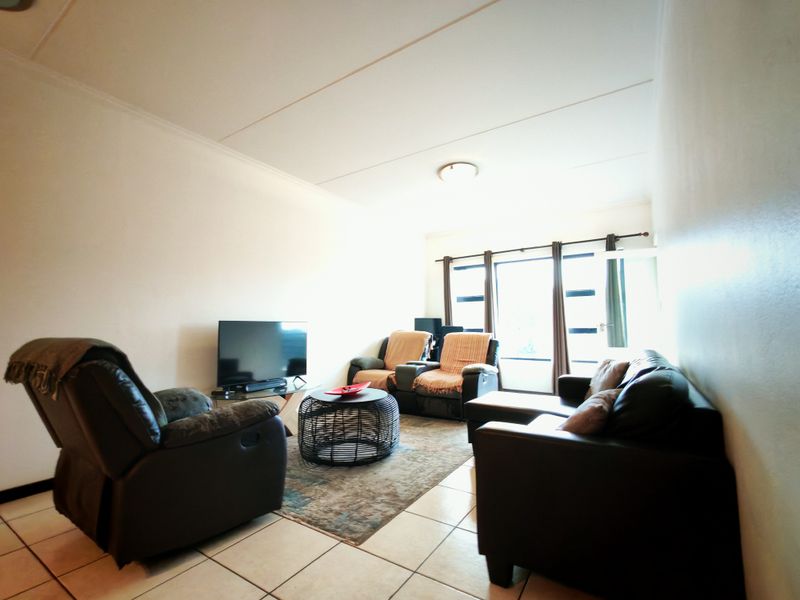 A functional living room featuring tiled flooring and a large window that allows for natural light.