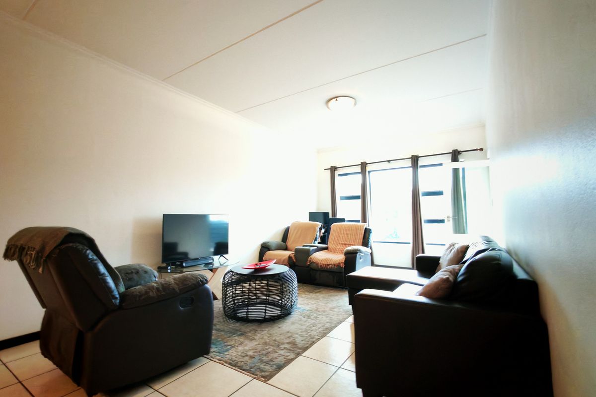 A functional living room featuring tiled flooring and a large window that allows for natural light.
