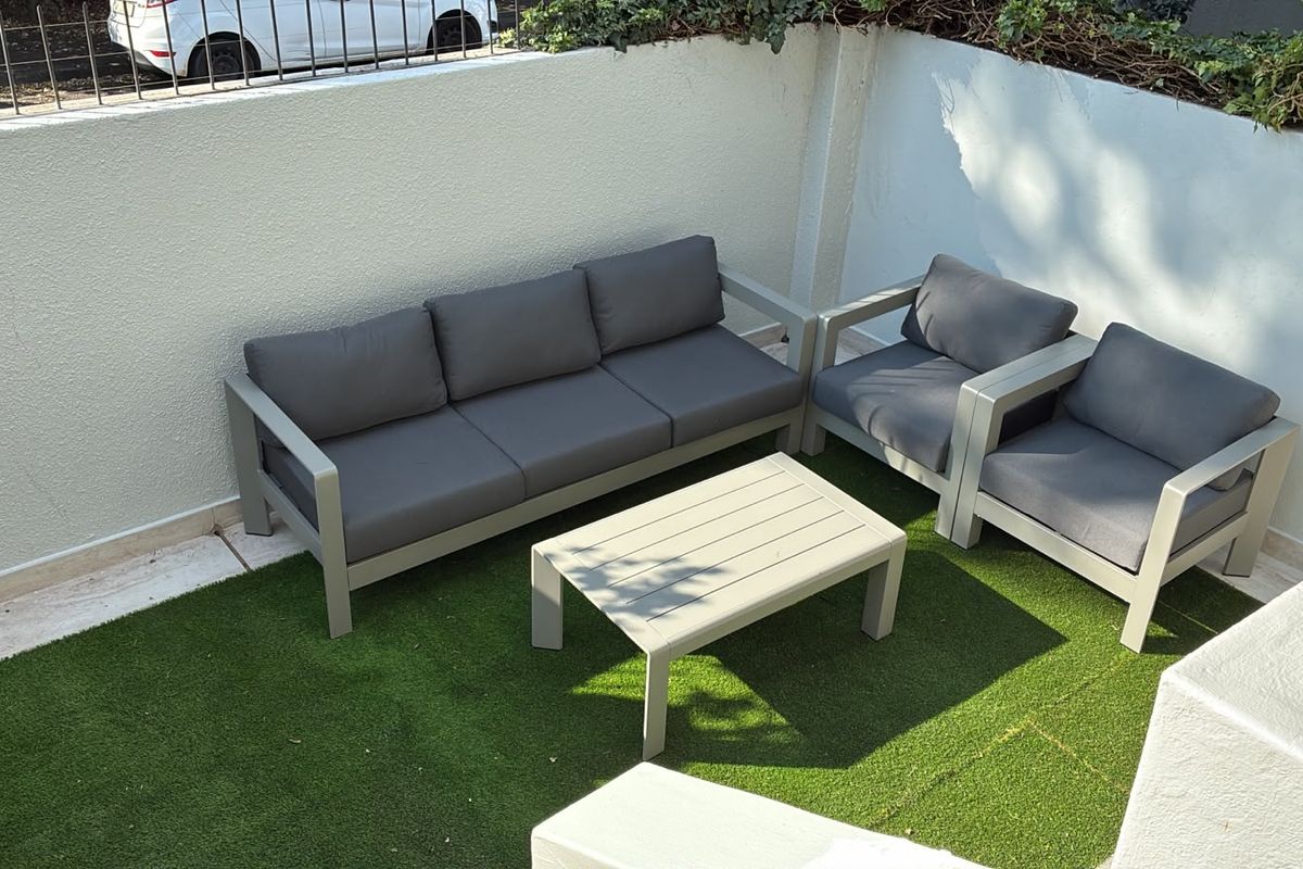 A private outdoor patio area featuring artificial grass surfacing and enclosed by a perimeter wall with metal railing.
