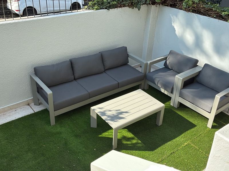A private outdoor patio area featuring artificial grass surfacing and enclosed by a perimeter wall with metal railing.