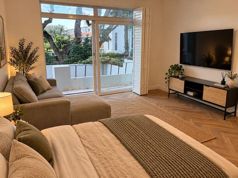 A well-appointed bedroom featuring elegant herringbone timber flooring and bi-fold doors that open onto a private balcony, providing ample natural light.