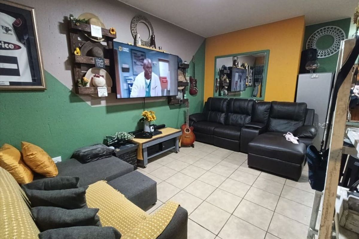A living room featuring ceramic floor tiles and multi-colored painted walls, providing a functional space for relaxation.