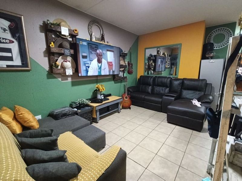 A living room featuring ceramic floor tiles and multi-colored painted walls, providing a functional space for relaxation.