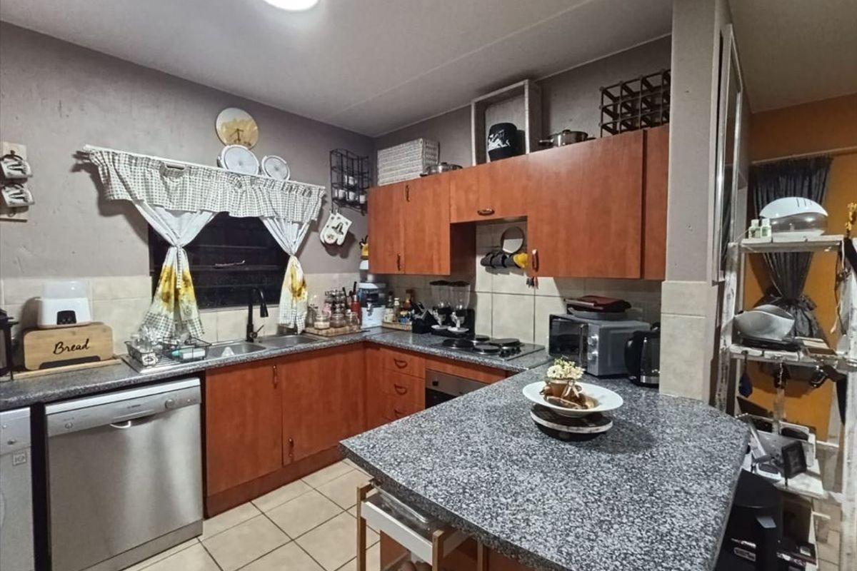 A functional kitchen featuring wooden cabinetry, granite countertops, a tiled backsplash, and built-in cooking appliances, offering a practical layout for daily meal preparation.
