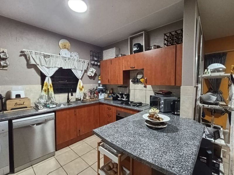 A functional kitchen featuring wooden cabinetry, granite countertops, a tiled backsplash, and built-in cooking appliances, offering a practical layout for daily meal preparation.