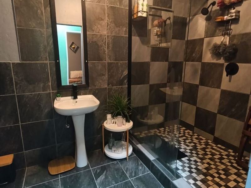 Modern bathroom featuring a walk-in shower with glass screen, pedestal basin, and contemporary dark tiled finishes throughout.