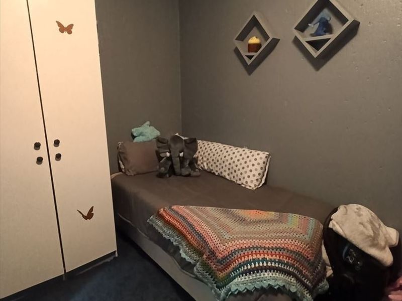 A compact bedroom featuring a built-in wardrobe and dark wall finishes, providing a functional space for a single bed.