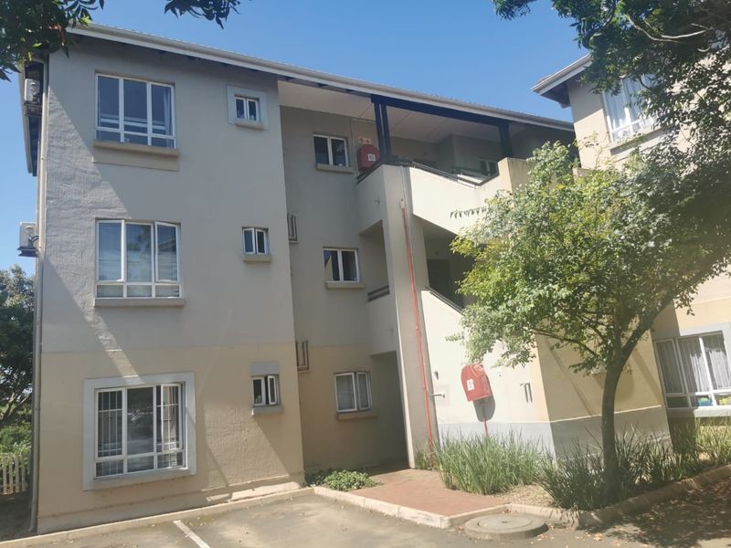 Exterior view of a multi-story apartment building featuring a paved entrance walkway, stairwell access, and functional fire safety equipment.